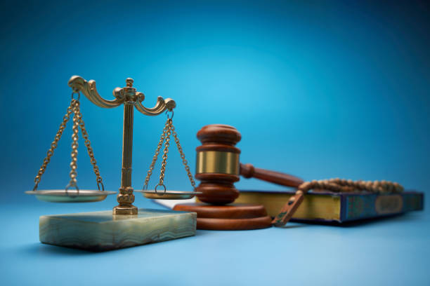 koran, prayer beads ,scale libra and gavel hammer against blue background