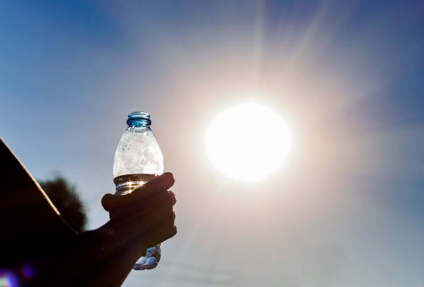 bottle-with-water-in-a-womans-hand-against-bright-sun-outdoors-climate-change-hotness-concept